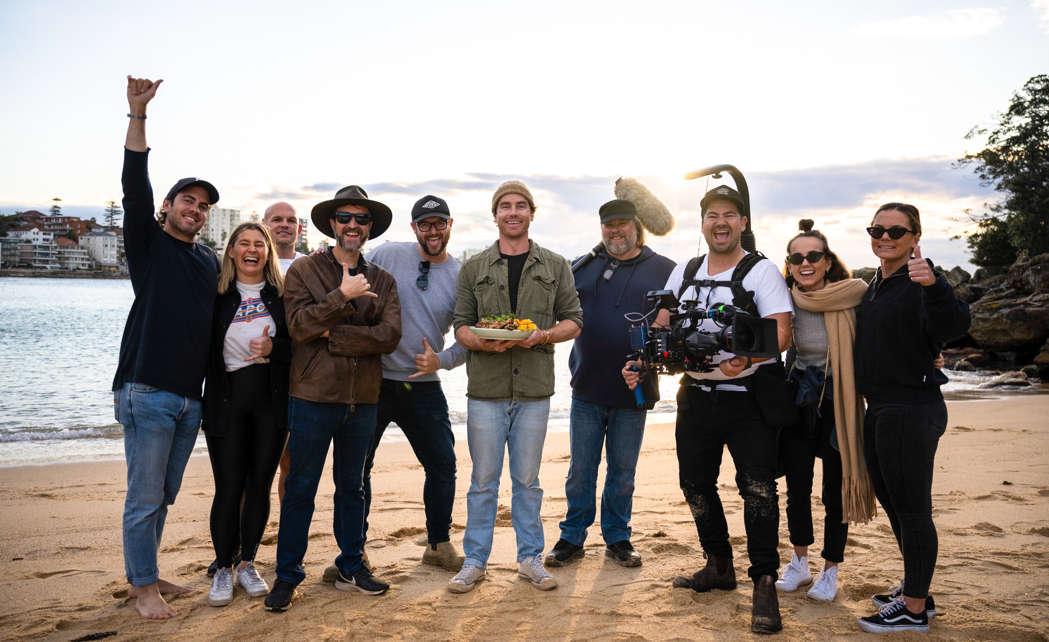 The Taste of Australia crew on location at the beach with Hayden Quinn, a camera rig and boom microphone